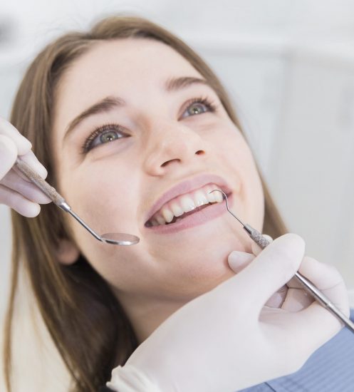 smiling-young-woman-having-teeth-examined-dentists (1)